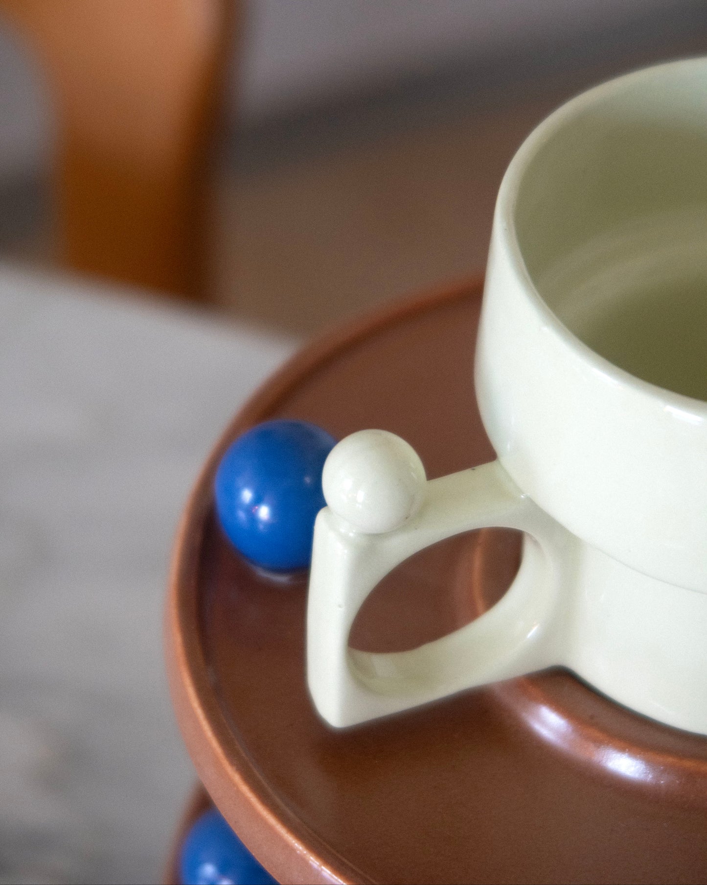White mug with a handle shaped like a person on a brown coaster