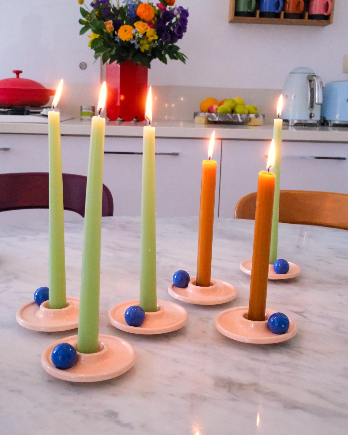 Set of six candle holders with lit candles on a kitchen counter.