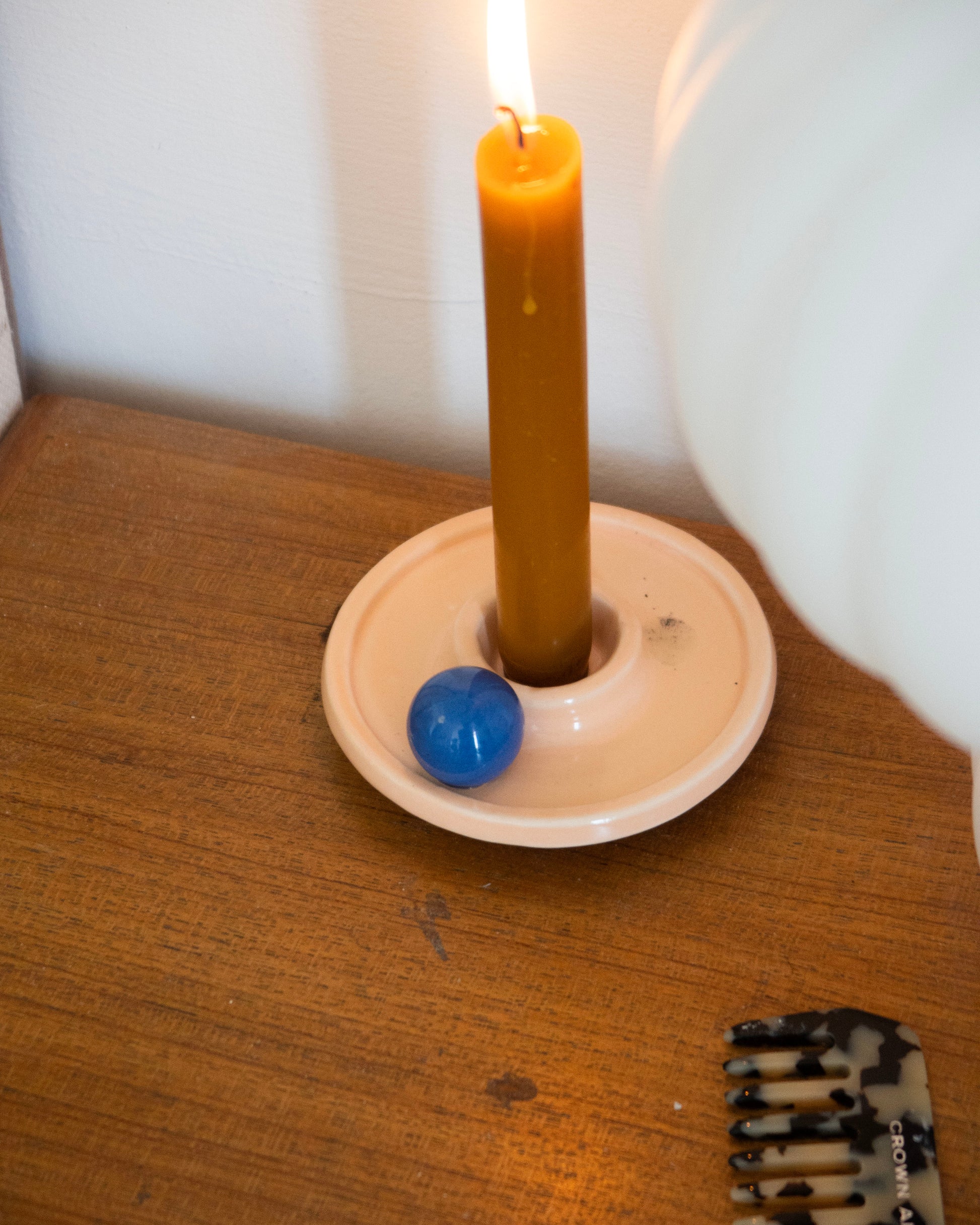 Candle in a holder with a blue ball on a wooden surface