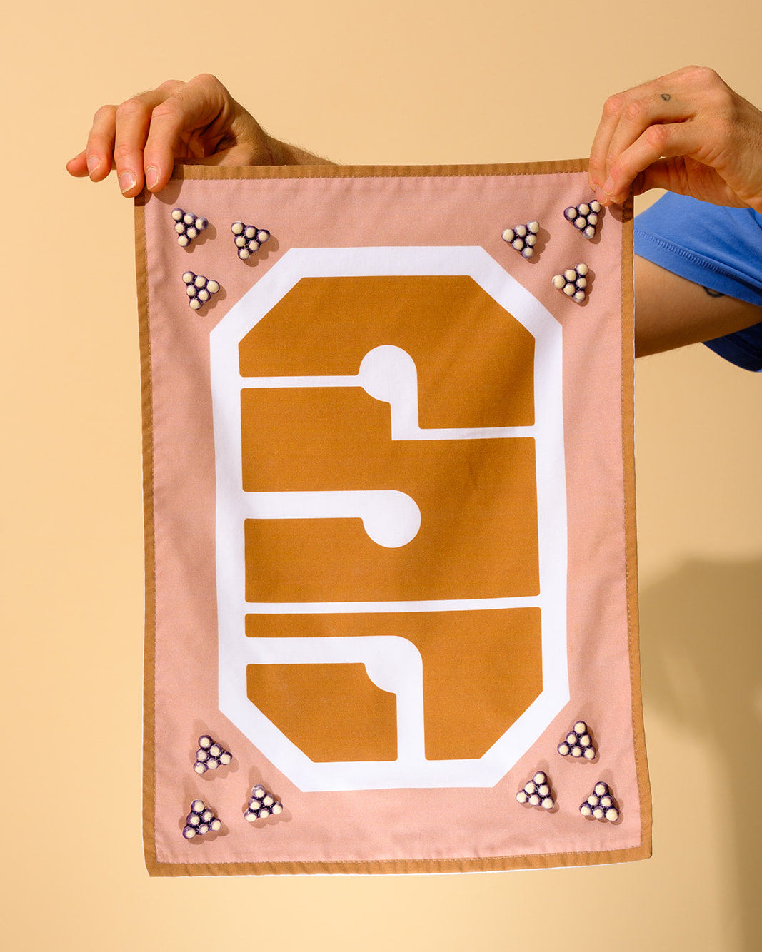Handmade modern challah cover with Hebrew typography and ceramic grape beads, designed in Tel Aviv for the contemporary Shabbat table.