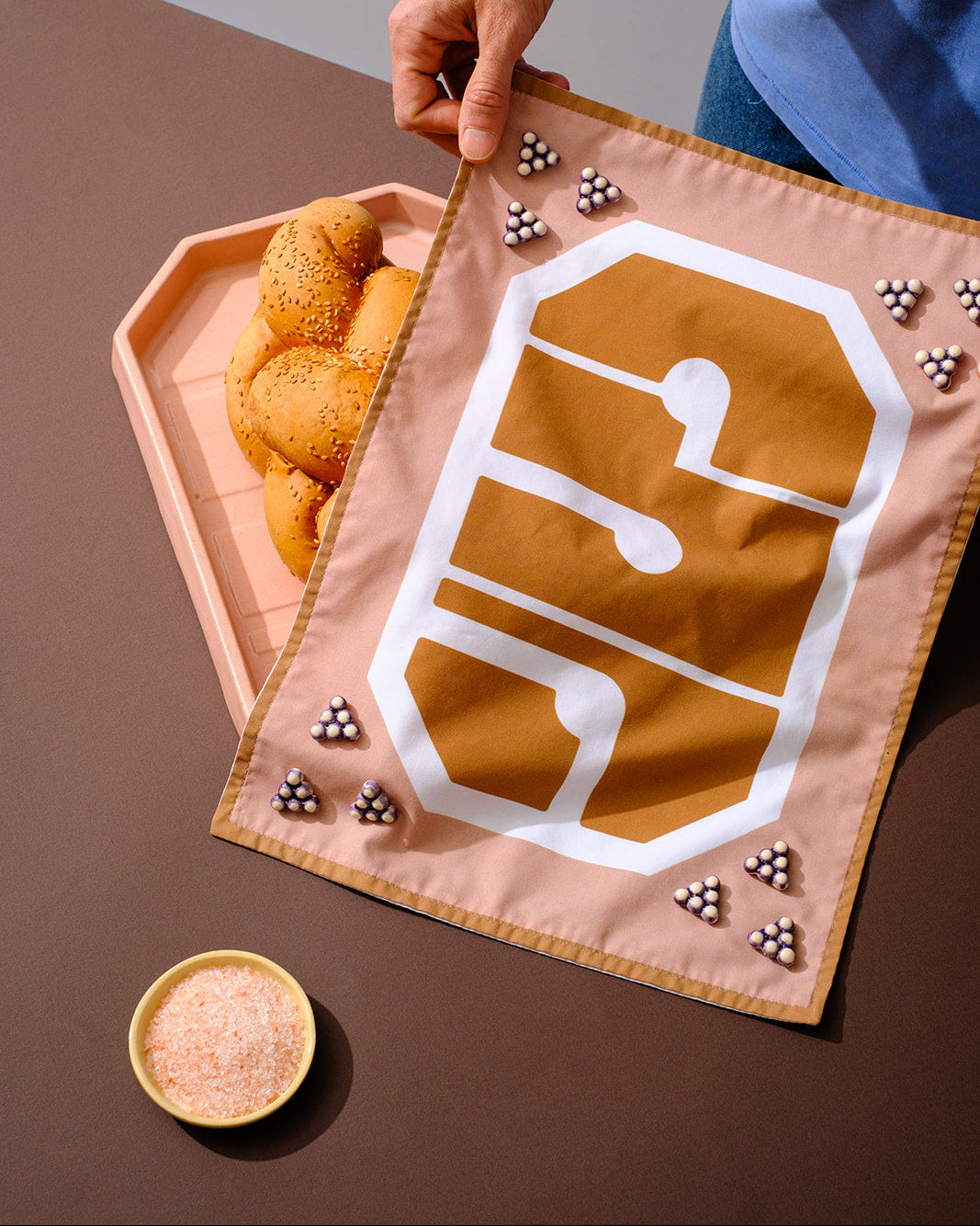 Contemporary challah cover inspired by Israeli visual culture, featuring Hebrew lettering and handcrafted ceramic details.
