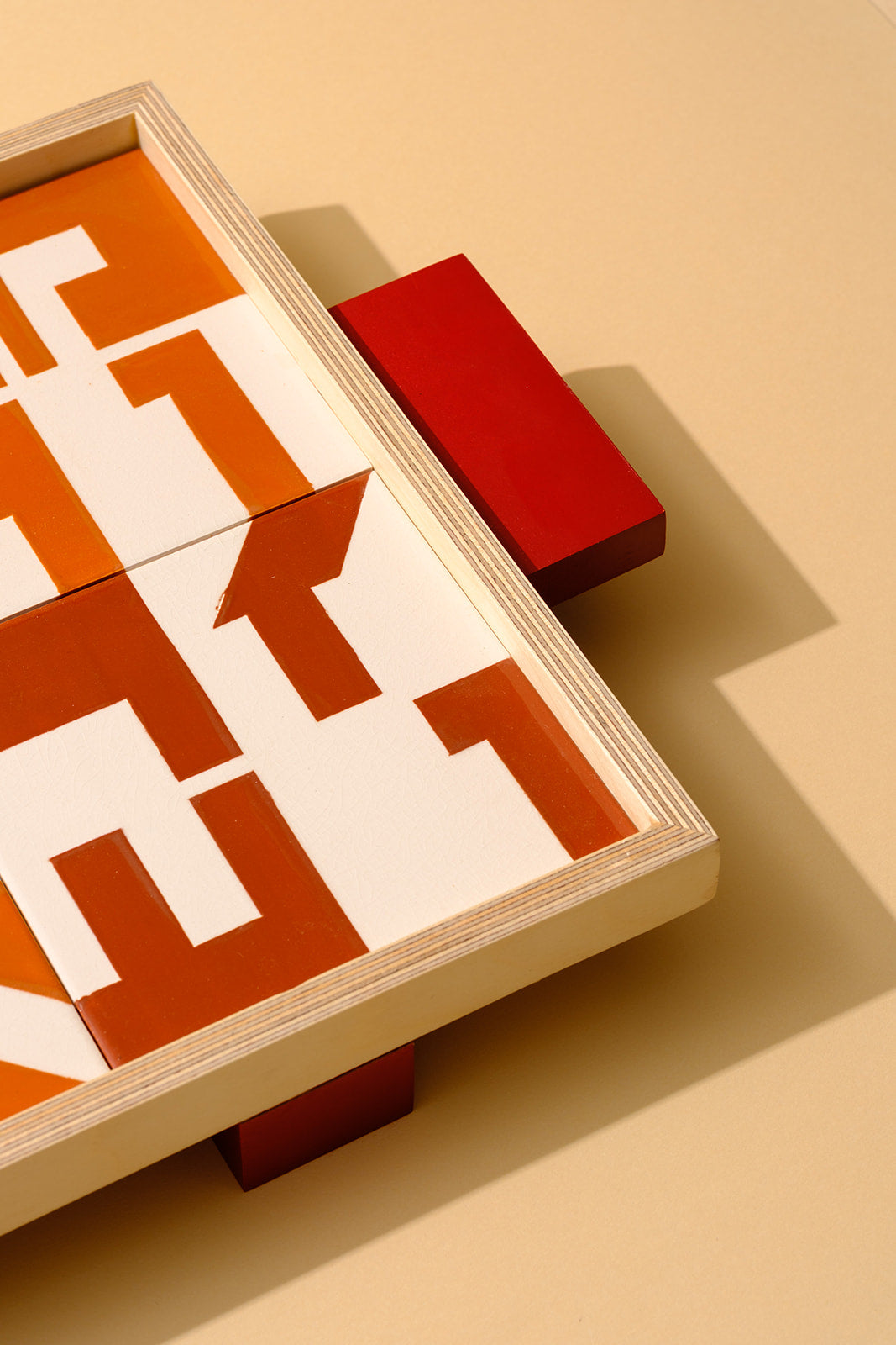 Wooden tray with hand-painted ceramic tiles displaying Hebrew names of traditional Passover Seder foods in a geometric design