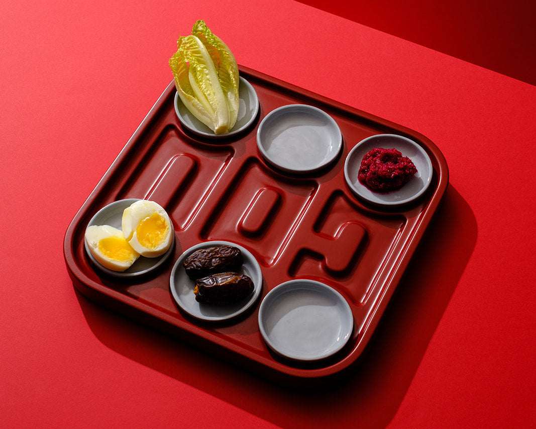 A handcrafted red wooden Seder plate featuring integrated ceramic bowls, designed as a contemporary interpretation of the traditional Passover ritual object