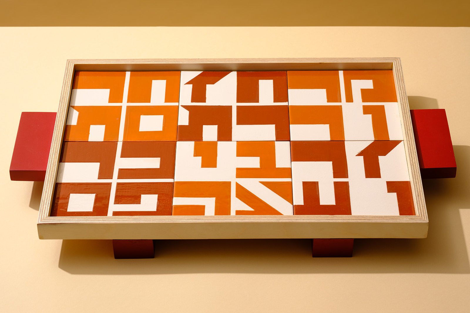 A wooden serving tray inlaid with hand-painted ceramic tiles, each featuring the name of a traditional Passover Seder food in Hebrew