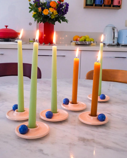 Set of six candle holders with lit candles on a kitchen counter.